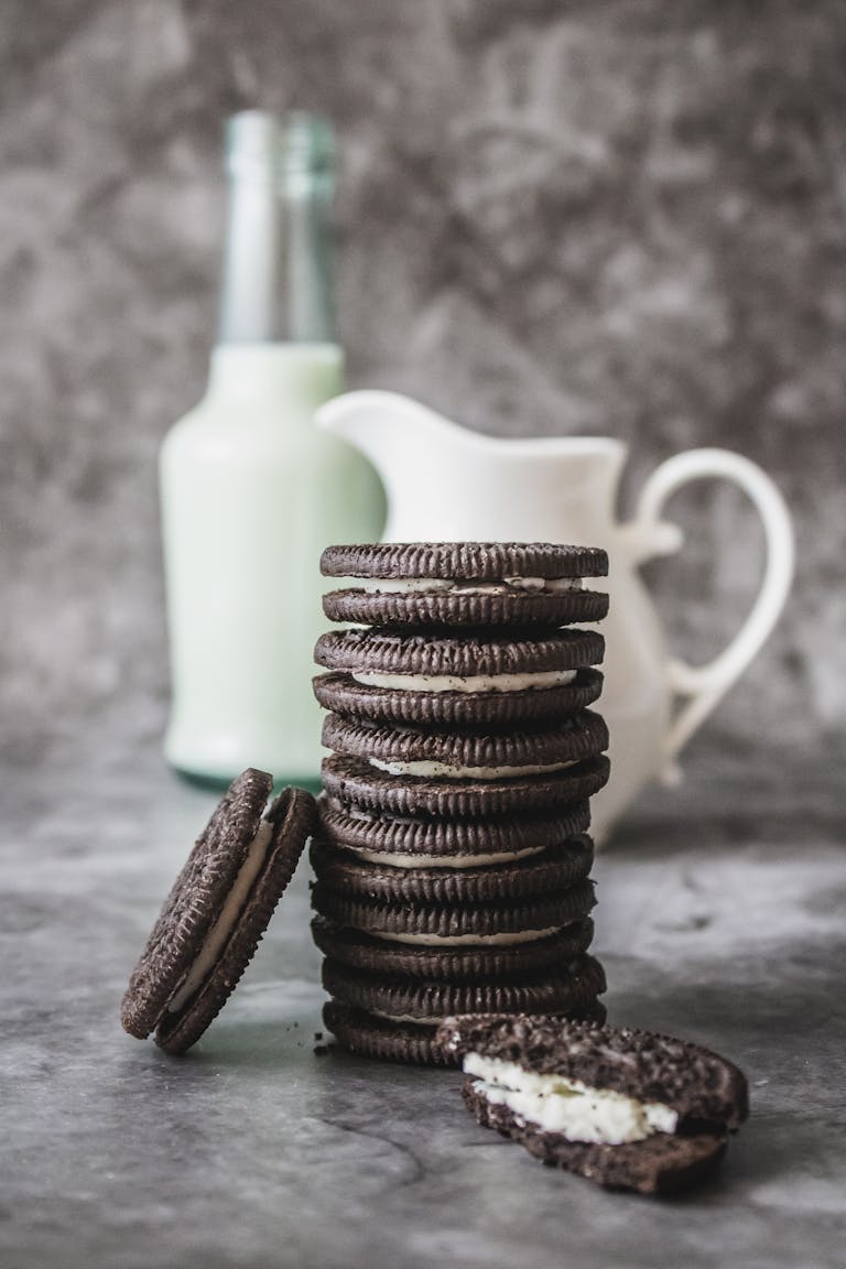 Delicious stack of chocolate cookies and milk bottle on a marble surface, perfect for an indulgent breakfast.